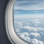 View of the clouds and blue sky from an airplane window seat during a flight