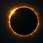 A total solar eclipse showing the moon completely covering the sun with a glowing white corona around the edge
