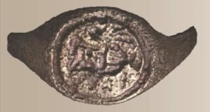 An ancient copper signet ring with Greek lettering and pottery imagery found in the Judean Desert.