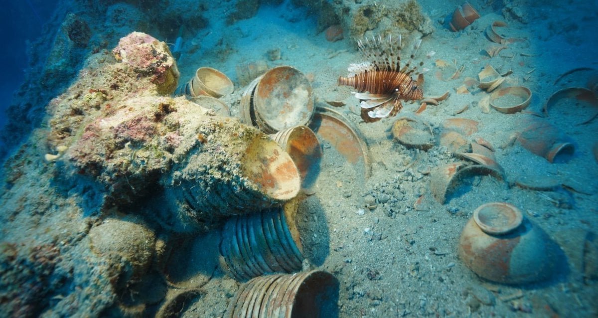 Underwater view of an ancient shipwreck in Turkey filled with thousands of red ceramic tableware pieces.