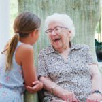 A healthy elderly person smiling while gardening in a sunny outdoor environment.
