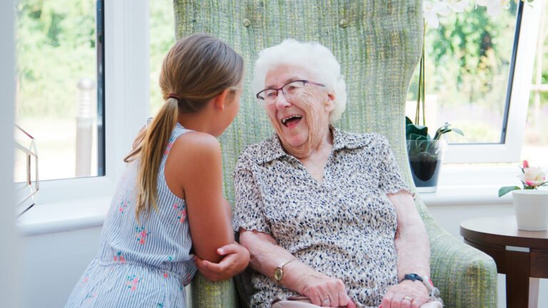 A healthy elderly person smiling while gardening in a sunny outdoor environment.