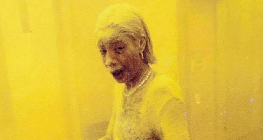 Realistic representation of a woman in professional attire covered in grey dust and ash in a New York lobby.
